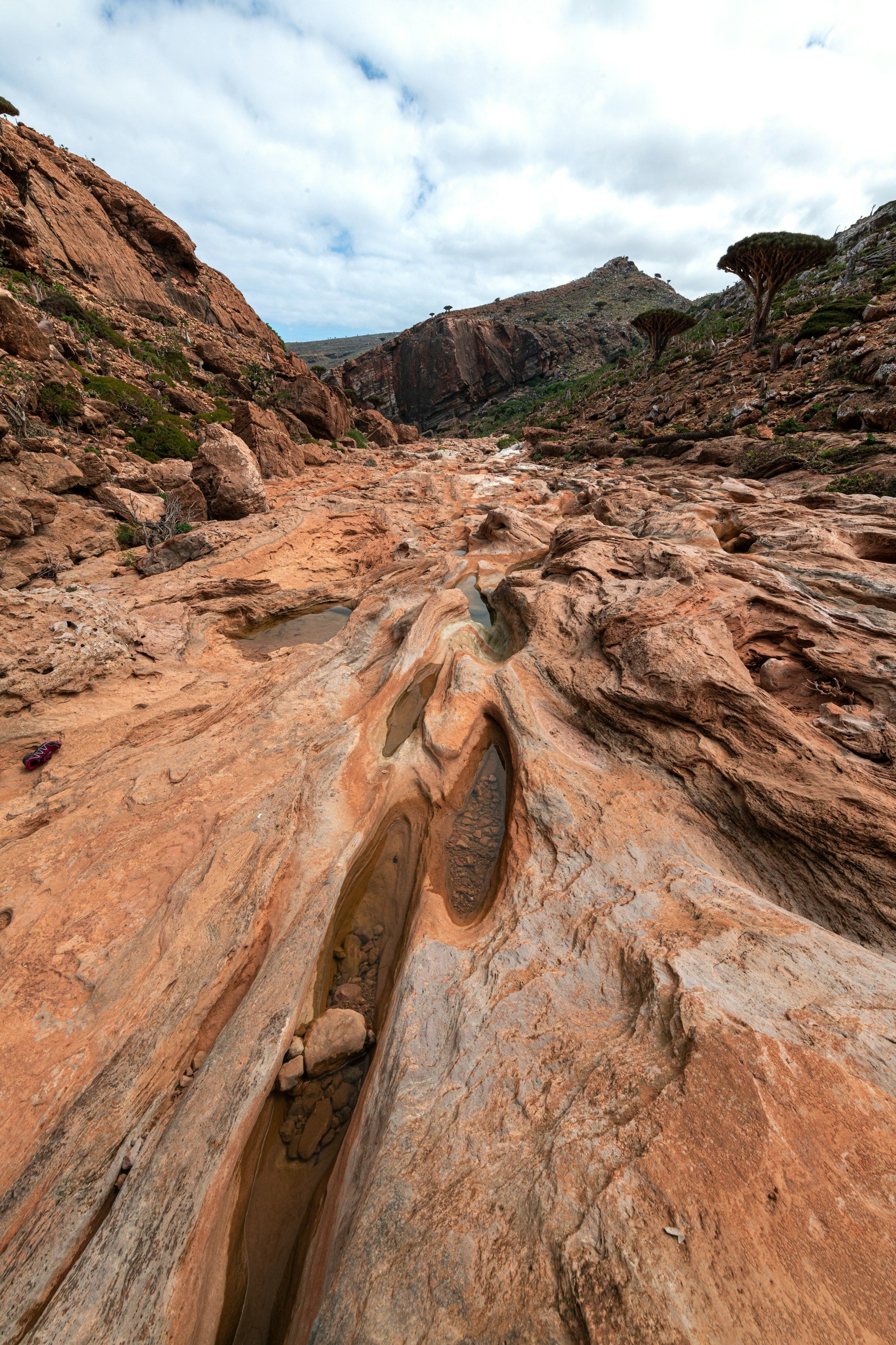 Chain of natural freshwater pools carved into red rock in a Socotra canyon
